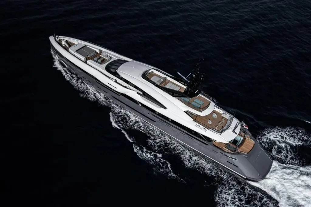 Aerial view of a large white luxury motor yacht underway on dark blue open water
