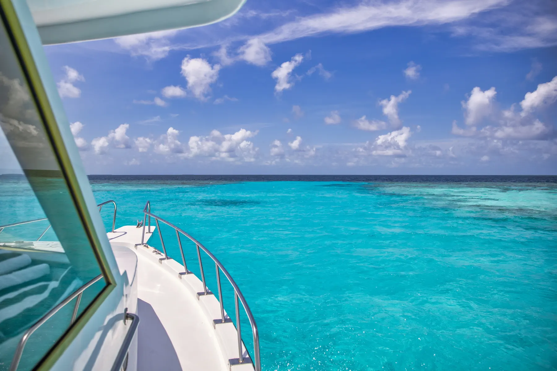 View from a yacht deck across turquoise water under a bright sky.